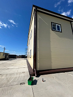 Коричневый водосток на бежевом фасаде здания