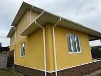 Жёлтый дом с белым водостоком Döcke Premium ПВХ, угловой вид с двумя трубами