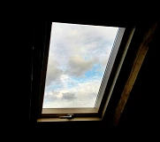 Внутренний вид мансардного окна Fakro с видом на облачное небо через остекление