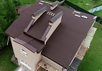 Вид на кровлю коттеджа с мансардными окнами и снегозадержателями