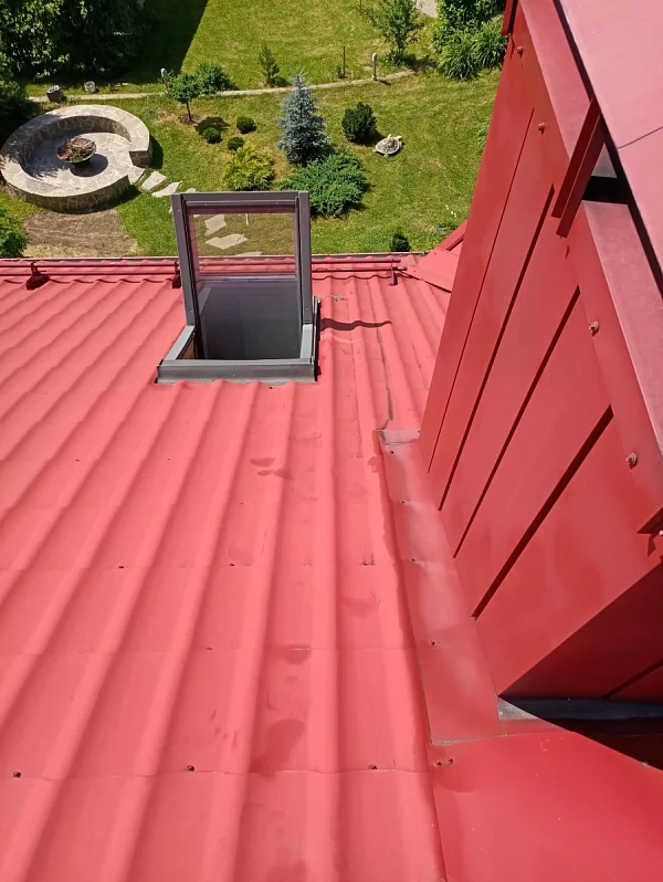 Красная крыша из металлочерепицы RAL 3011 с мансардным окном