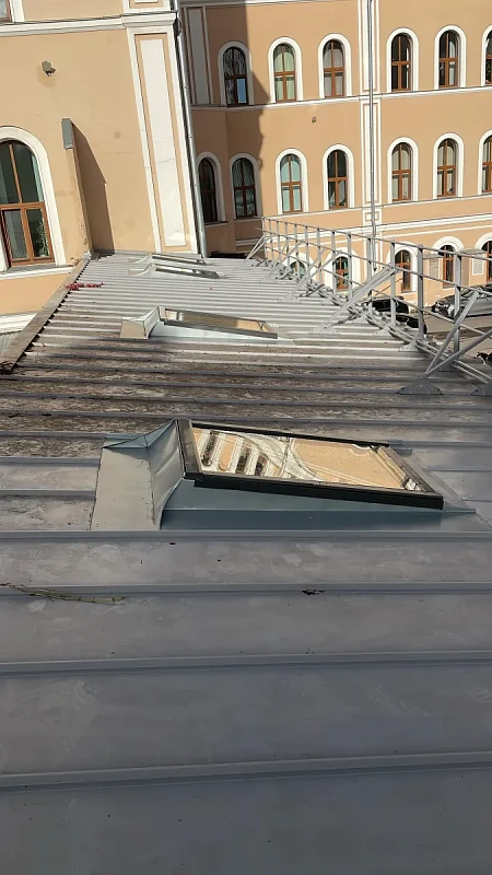 Мансардные окна на фальцевой кровле здания с арочными окнами