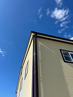 Фасад здания с окнами и коричневым водостоком