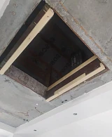 Открытый чердачный люк с деревянной рамой в бетонном потолке
