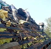 Рабочие снимают старое кровельное покрытие и утеплитель с крыши