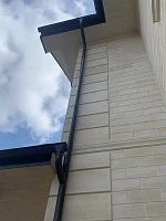 Водосточная труба Grand Line на углу дома с кровлей Металл Профиль Трамонтана