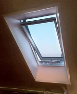 Вид мансардного окна изнутри чердака с естественным освещением