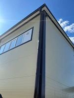 Угол здания с коричневой водосточной трубой