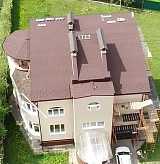 Общий вид коттеджа с новой кровлей и строительными лесами