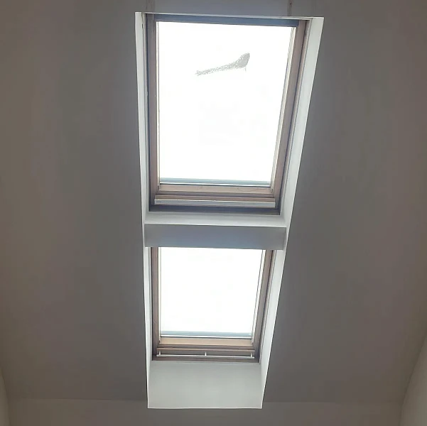 Два мансардных окна в потолке, вид изнутри помещения с белыми откосами